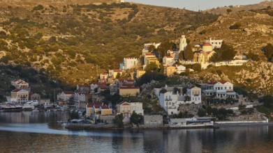 Small coastal town, surrounded by vegetation, reflected in the water, Symi Town, Symi, Dodecanese,