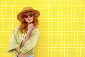 Fashionable influencer posing confidently against a vibrant yellow tiled wall, pointing with her
