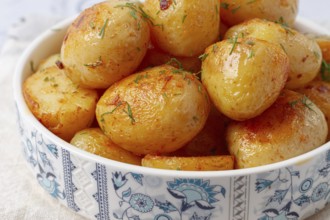 Baked new potatoes, with butter and dill, on a white plate, at home, no people