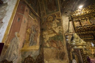 Richly decorated altar table and frescoes in a church showing detailed religious scenes, Thari