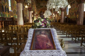 Large church room with a portrait of Jesus and floral decorations on an altar, surrounded by