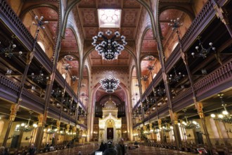 Artfully decorated interior with Torah shrine, tourist with traditional headgear, kippah, Great