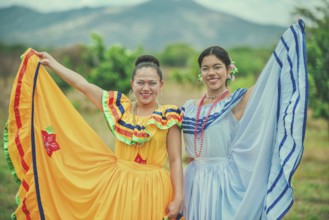 Portrait of two Hispanic women wearing cultural folkloric costume in a field. Two smiling Hispanic