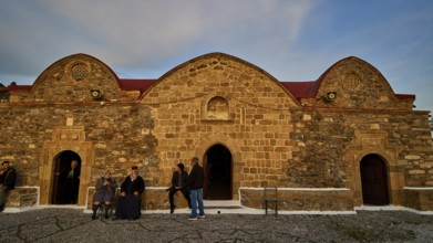 Old stone building in the evening light, people standing in front of the historic facade, Easter