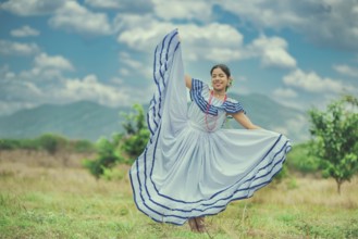 Young Nicaraguan woman in traditional folk costume in a field, smiling at camera