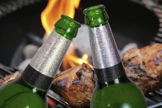 (Photomontage) Two beer bottles in front of grilled meat