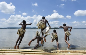 Boys jump in the Brahmaputra river wearing polystyrene sheets to keep themself float in the water