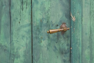 Old green wooden door with peeling paint and metal handle, metal latch, Croatia, Europe