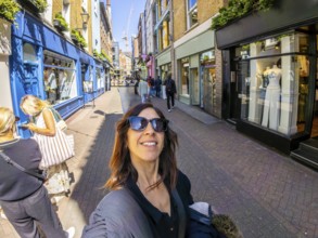 Happy tourist taking a selfie while walking in carnaby street, a popular shopping street in
