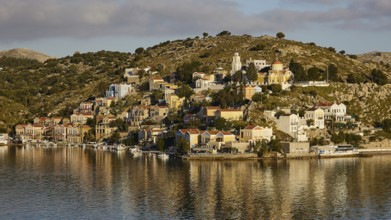 Pretty buildings on a hilltop island reflected in the water. Mediterranean atmosphere in the