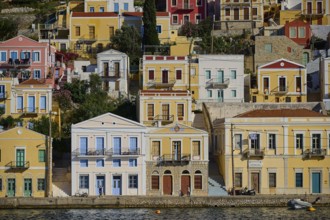 Colourful houses along a water with reflection, Symi Town, Symi, Dodecanese, Greek Islands, Greece,