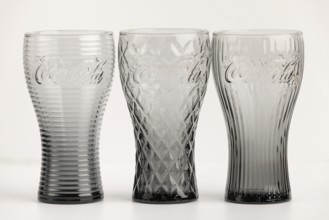 Three stylish, differently designed cola glasses in transparent and black tones