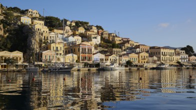 Coastal town with colourful houses on the bay, boats in the calm water, Symi Town, Symi,
