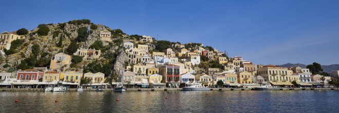 Colourful coastal houses reflect in the calm sea under a clear blue sky and create a picturesque