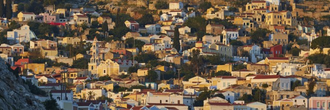 Houses standing close together in warm morning light on a hill, Symi town, Symi, Dodecanese, Greek