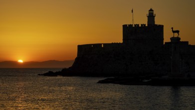 Majestic silhouette of a fortress against a glowing sunrise, dawn, Fort of Saint Nikolaos, Mandraki