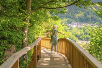 A person walks with outstretched arms on a path and enjoys the view, Panorama Holzsteg, Calw, Black