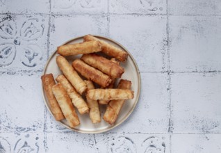 Fried spring rolls with cheese, on a plate, with cream sauce, no people