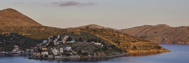 Island in the morning with hills and view of the calm sea in the warm light, Symi Town, Symi,