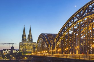 Cologne Cathedral, illuminated in the evening. Hohenzollern Bridge, railway bridge over the Rhine.