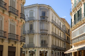 Elegant buildings with curved balconies along a sunny street in Malaga, Spain, Europe