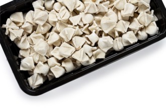 Traditional Turkish dumplings, raw, in a black container, white background, isolate, top view, no