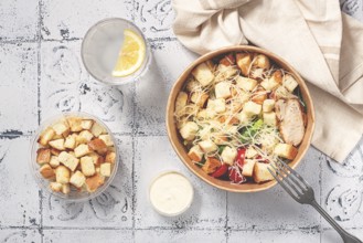 Caesar salad in a paper container, take it on the way, with sauce and croutons, on the table,