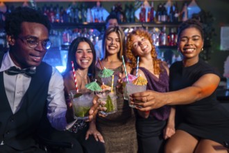 Diverse group of friends raising glasses of mojitos in celebration at a vibrant nightclub, enjoying