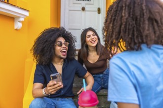 Three cheerful friends enjoying a lively conversation and refreshments while sitting on vibrant