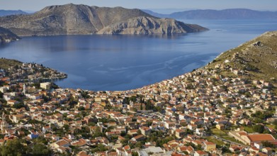 View of a town surrounded by mountains and a calm sea coast, Symi Town, Symi, Dodecanese, Greek