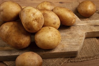Raw potatoes, scattered on a chopping board, close-up, no people