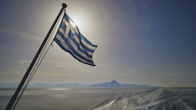 Greek flag in the foreground, over a widening sea under a blue sky, crossing Rhodes to Symi, ferry,