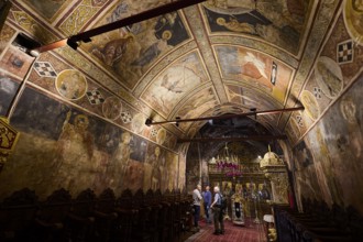 Church interior with detailed wall frescoes and vaulted ceiling, rich religious decorations, Thari