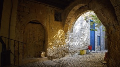 Weathered stone arcade with rays of light falling through an old archway, Rhodes Old Town, Rhodes,