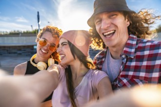 Three cheerful young friends taking a selfie outdoors, soaking up the sun and enjoying a vibrant