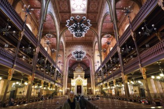 Artfully decorated interior with Torah shrine, tourist with traditional headgear, kippah, Great