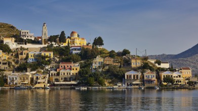 Hilltop town by the water with church and Mediterranean architecture, Symi Town, Symi, Dodecanese,