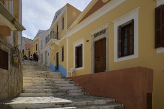 Narrow stairway flanked by yellow houses, in the sunshine, Symi Town, Symi, Dodecanese, Greek