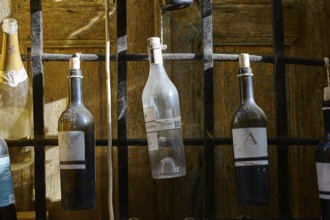 Various bottles hanging from a black metal grid, Symi Town, Symi, Dodecanese, Greek Islands,