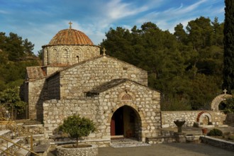 Historic stone church under a blue sky surrounded by trees, Thari Monastery, Moni Thari, near