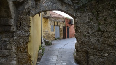 Abandoned corridor with yellow and red walls and stone arches, Rhodes Old Town, Rhodes, Dodecanese,