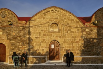 People sitting in front of a stone church in warm light and quiet surroundings, Easter 2025, Church