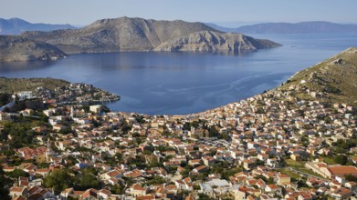 Sweeping views over a town nestled between mountains and calm sea, Symi Town, Symi, Dodecanese,