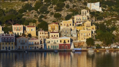 Colourful buildings along the water with some boats on the shore, Mediterranean scenery, Symi town,