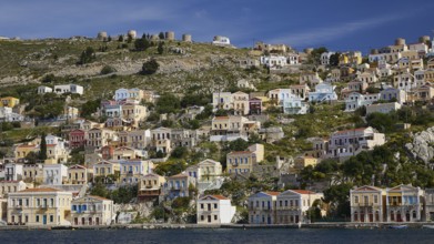 Village full of colourful houses on a hill overlooking the coast and the sea, Symi Town, Symi,