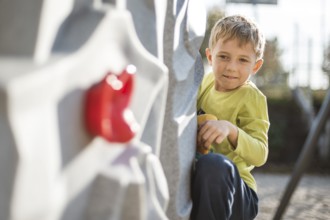 Seven year old boy climbing at artificial wall