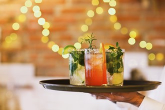 Two cocktail glasses on tray on wooden bar counter