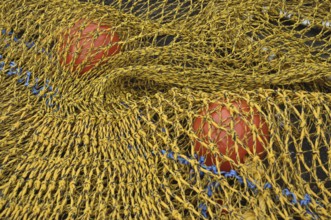 Close-up of a yellow fishing net with red floats and blue rope
