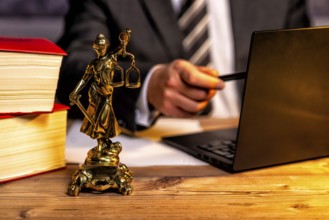 Office of a lawyer with books and a statue of Lady Justice, goddess Justitia, on the desk