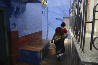 Woman carrying bucket in narrow lane, jodhpur, rajasthan, India, Asia